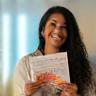 Amira Ahmed, smiling with presentation material